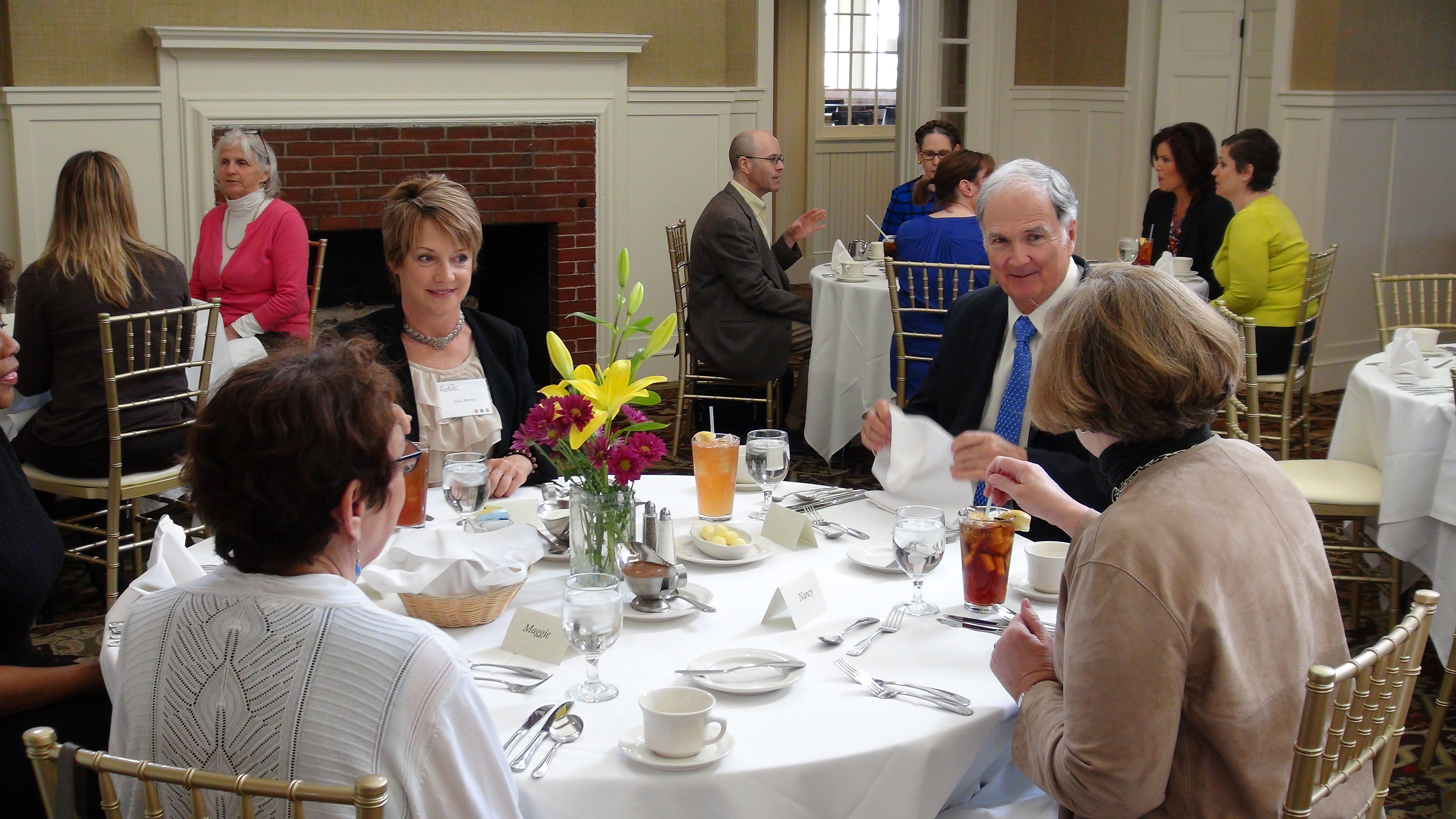 four people seated at a formal dining table in business attire